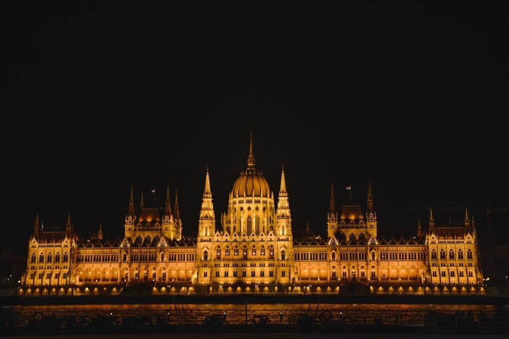 Travel Poland to Hungary: admire Budapest’s illuminated Parliament at night, a must-see landmark on a budget-friendly European journey.